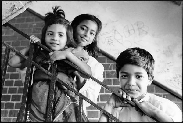 Black and white photograph of children leaning against railings