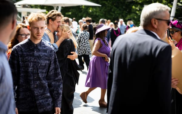 Visitors and students mingling outside the Southbank Centre, one person is kissing another person on the head