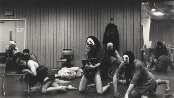 Performers in masks crawling around a room as part of a rehearsal of Furies.