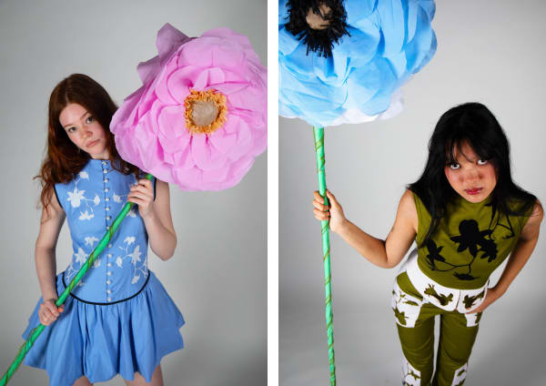 Young female models in fitted dress / jumpsuit with oversized paper flowers.