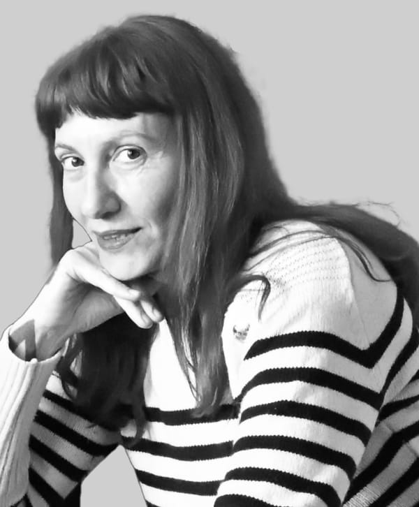 A greyscale portrait of Betti, chin leaning on on hand.