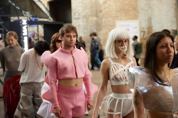 Performers in sculptural garments walk among show guests at CSM Shows.