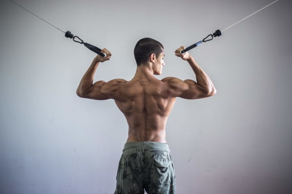 Photograph of a shirtless muscular man using gym equipment