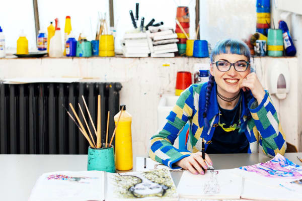 A smiling student with blue hair working in her studio