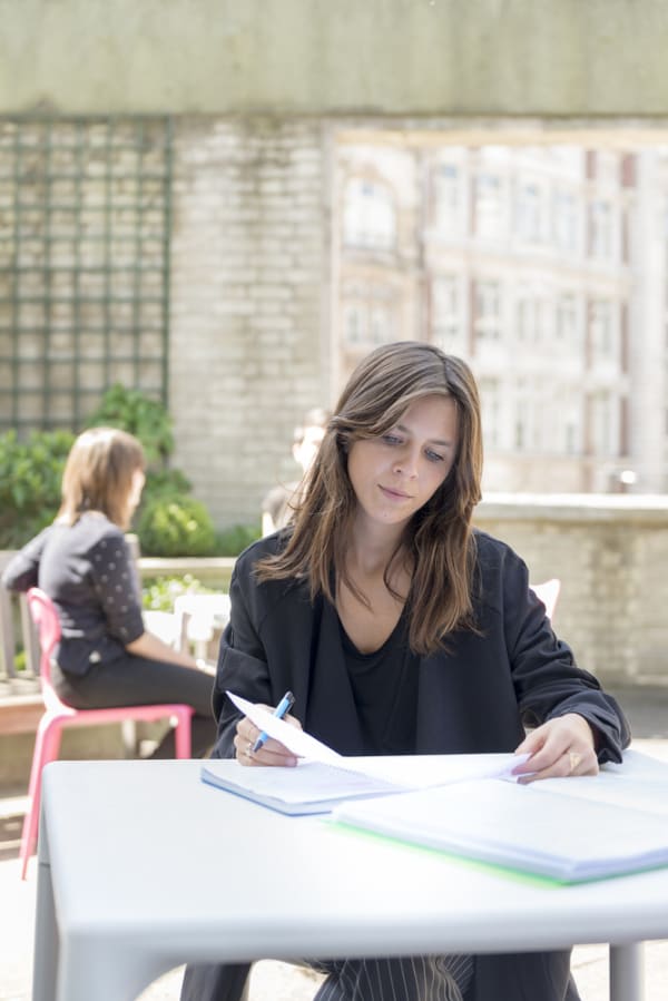 Woman sat outside looking at her notepad. MSc Applied Psychology in Fashion, Interview with Alexia-Chloe Brun, Case study. Copyright holder: Ivan Jones