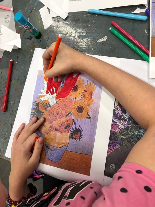 birds eye view of a students arm drawing on top of a pre-existing image of Van Gogh's sunflowers. 