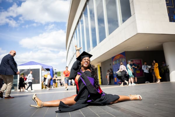 A graduate doing the splits outside the Southbank Centre
