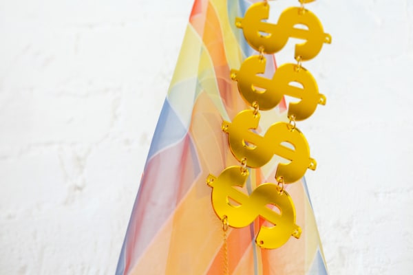 gold metal dollar signs over pastel striped textile
