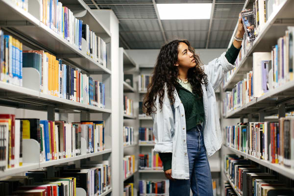 Student by library bookshelves.