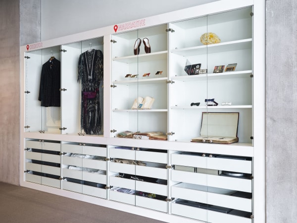 White shelves with various objects on, such as a dress, shoes, books and other garments.