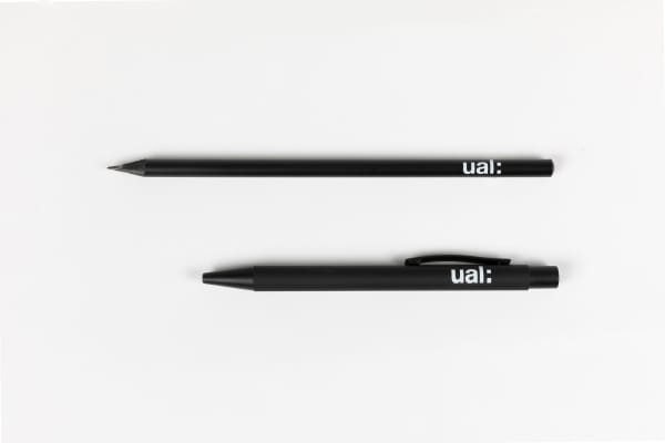 A black pencil and pen with white UAL logo laid flat on a plain white surface.