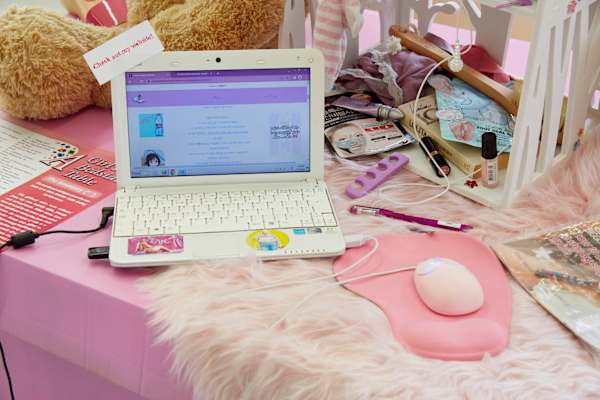 Old white laptop on a pink background