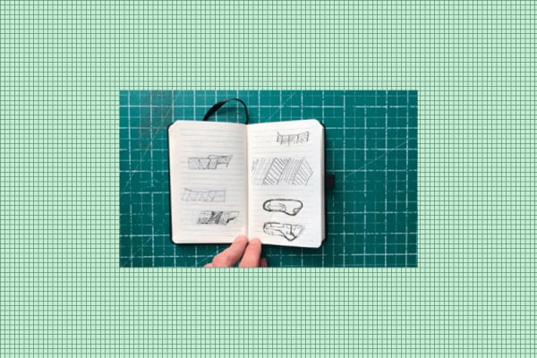 a small notebook with sketches, resting on top of a green cutting board