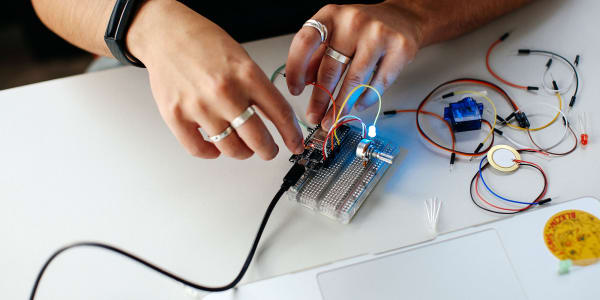 Close up image of student working with computational equipment, wires and light bulbs