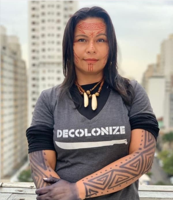 Image of indigenous artist in Brazil wearing a t-shirt saying 'decolonize'
