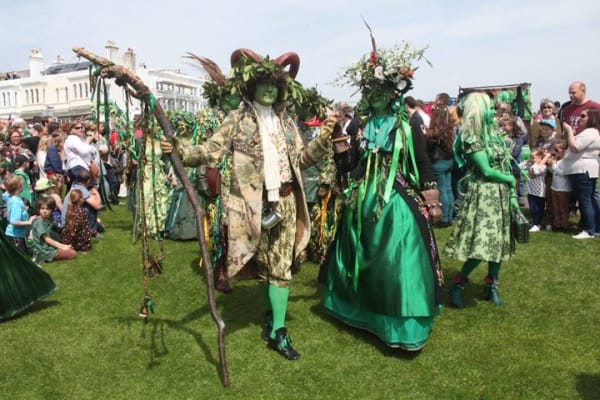Man dressed in costume of plant greenery and a painted green face.