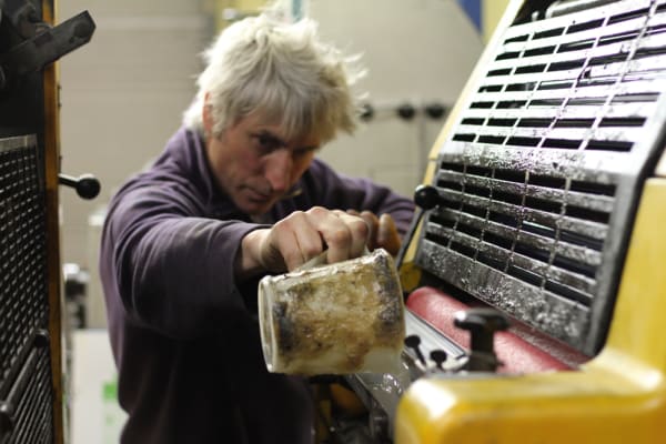 A person pouring ink into a printing press