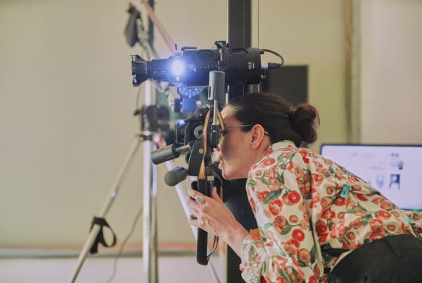 Student using a camera and other technical equipment within a studio space.