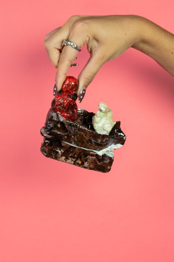 A hand holding a piece of cake