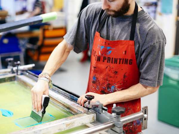 Technician screen printing with blue ink in the workshop.