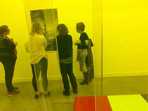 Photo of a group of people looking at a painting with a yellow wash over the picture
