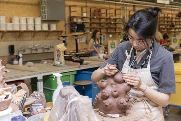 Students working with clay and ceramic pieces on display inside the Ceramics Workshop at Central Saint Martins