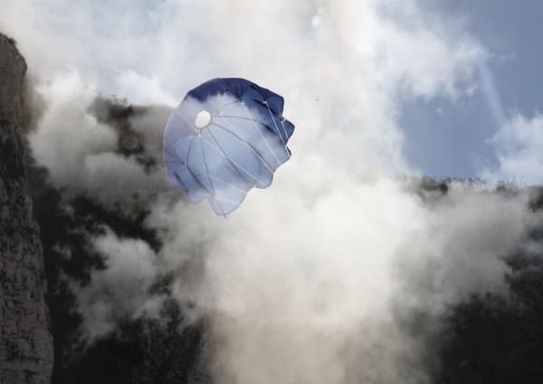 A blue parachute surrounded by clouds of mist