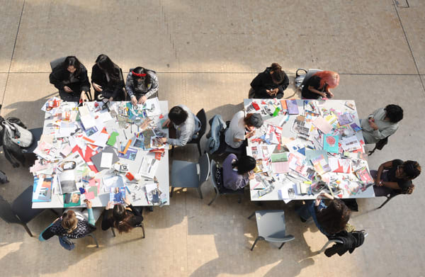Overhead shot of people sitting at tables making zines.