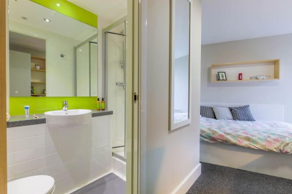 Standard room view of 3/4 bed, with full length mirror and entry to the ensuite, showing shower, large mirror, sink and toilet.