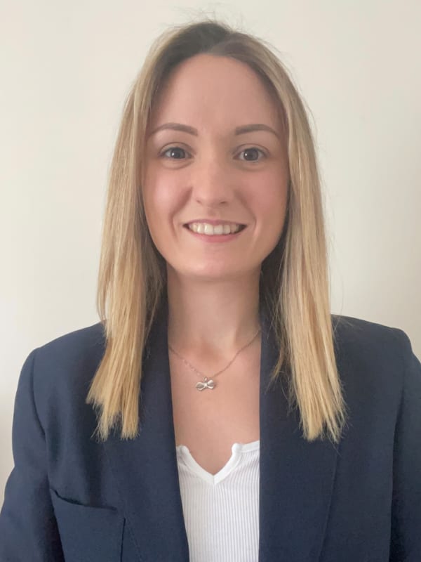Woman in formal attire standing against a white background