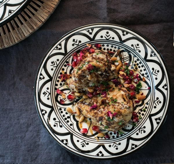 A decorative plate with a meal garnished with pomegranate and rose petals 