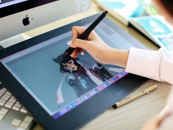 Student creating a digital illustration using a stylus and graphics tablet.