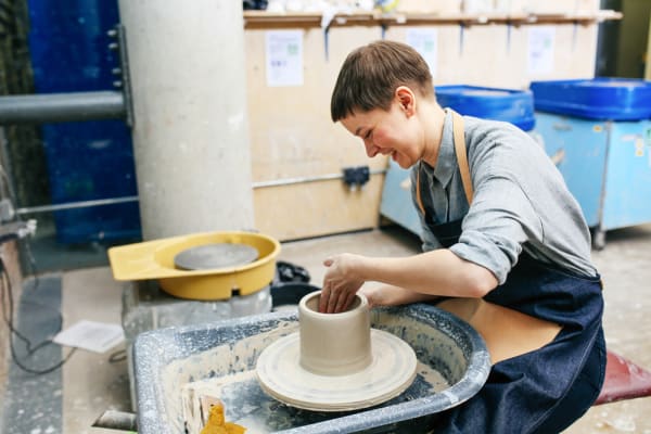 Student at a potter's wheel working with clay