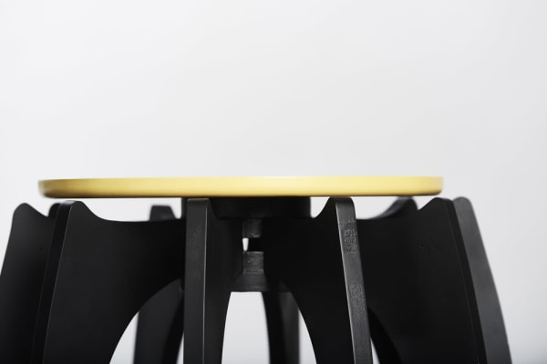 Stool prototype with black legs and a pale yellow seat
