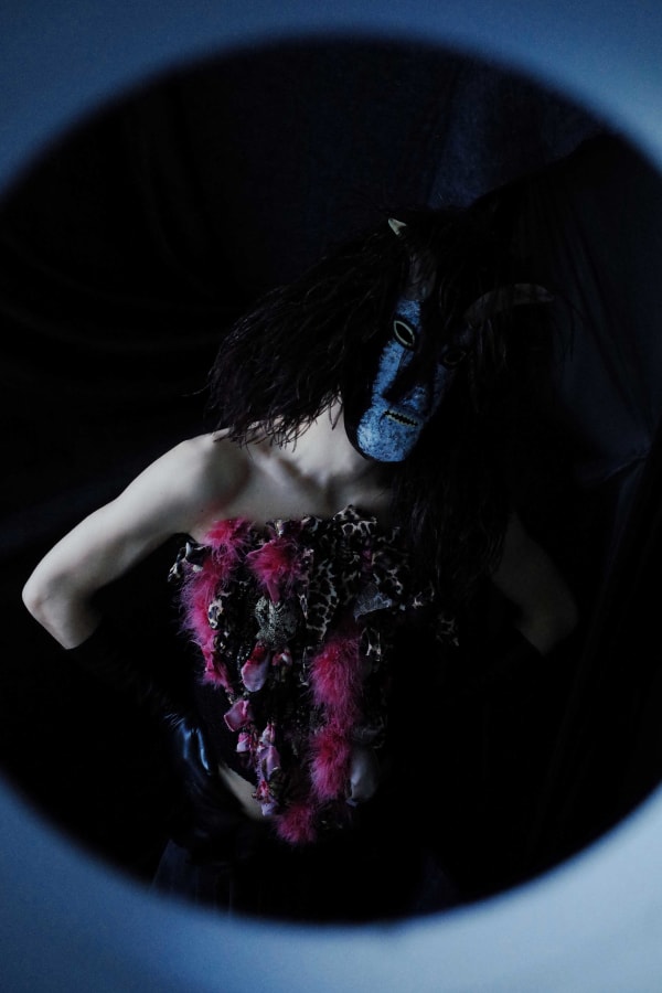 Figure wearing dark garments and dark mask