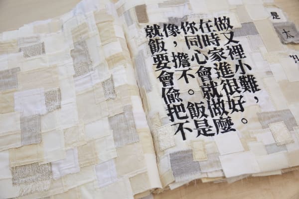 A book of fabric with has Mandarin inscriptions stitched onto it
