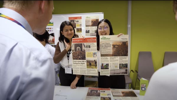 A person looking at two people holding up a chart