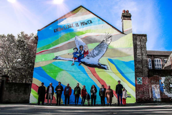 A mural on the side of a terrace showing three children riding a goose, under the words 