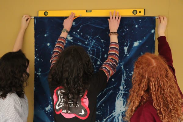 A photograph of 3 curators installing an artwork