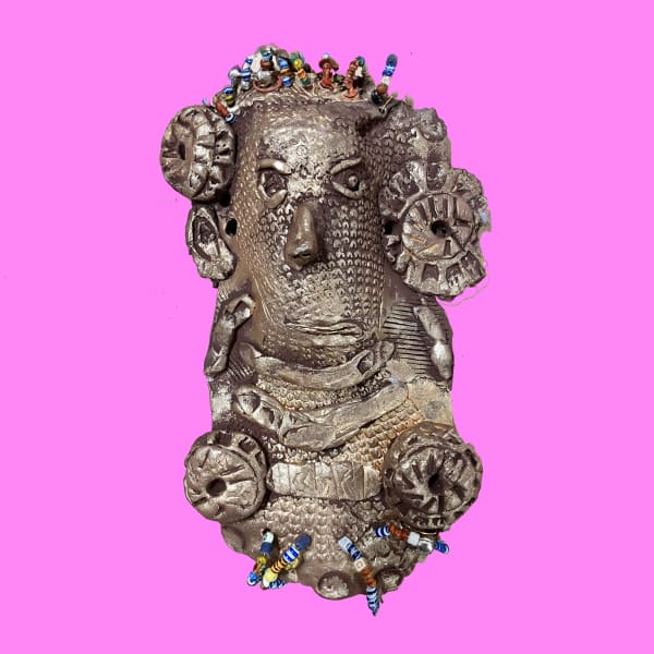 bronze mask with bead detail, on a pink background⁠