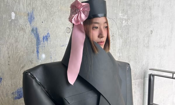 A model in an editorial shoot wearing an oversized tailored jacket and matching hat