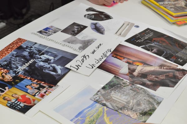 A table laid out with cards and colourful printed materials and images, plus some pink post-its with Japanese writing.