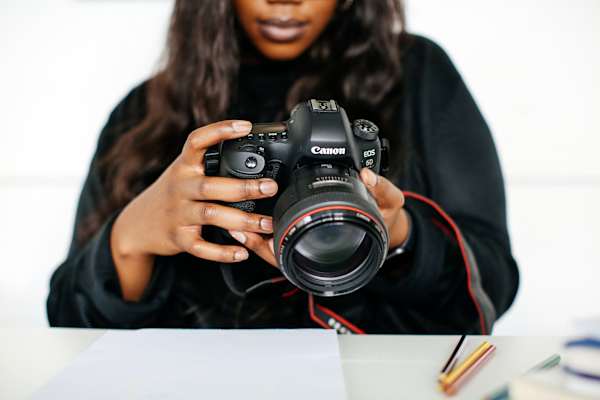 Person looking down at images on a black camera.