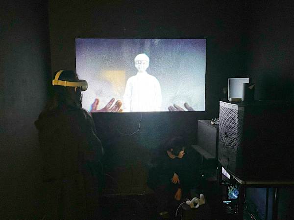 Visitor wearing a VR headset experiences an immersive film projected onto a screen.