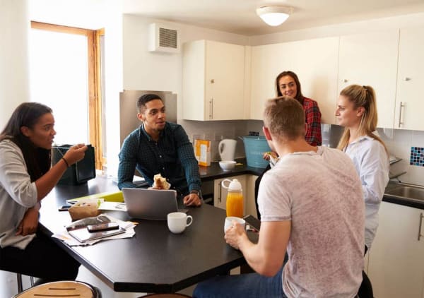 Group of students gathered in a kitchen talking 
