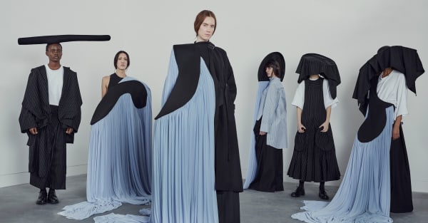 Female models wearing floaty pale blue skirts that trail across the floor.