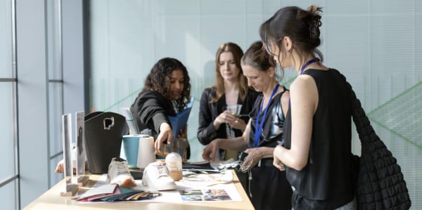 A group of people gathering around a table, looking at various printed materials and publications laid out on a table. 