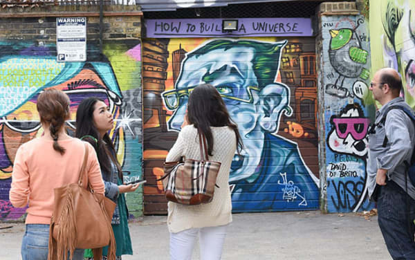 Group of people looking at a wall with graffiti on