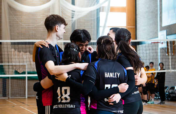 A group of volleyball players gather in a huddle.