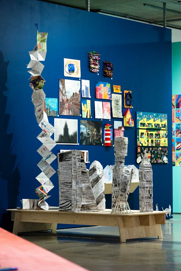 Upright sculptures on a plinth and arworks mounted on a navy blue wall inside the gallery space.